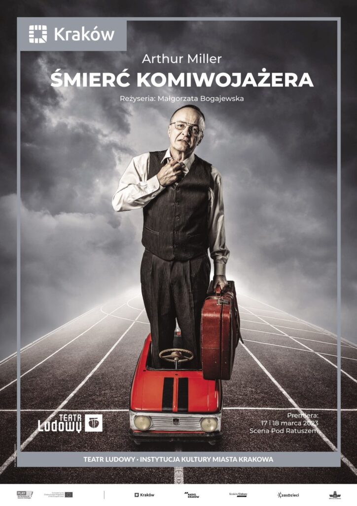 Plakat do spektaklu Śmierć komiwojażera. Druk pionowy z ramą będącą identyfikacją miejską, w lewym górnym rogu logo miasta Krakowa u dołu napis „Teatr Ludowy Instytucja Kultury Miasta Krakowa”. Pod napisem logotypy partnerów i sponsorów Teatru. Po środku plakatu zdjęcie kolaż graficzny, trzech aktorów. Szare tło fotograficzne i fotomontarz ścieżki do biegów sportowych. Aktor w średnim wieku ubrany w elegancką koszulę i garniturowe spodnie z kamizelką stoi nogami w zabawkowym samochodziku dla dzieci, w ręku trzyma walizkę.