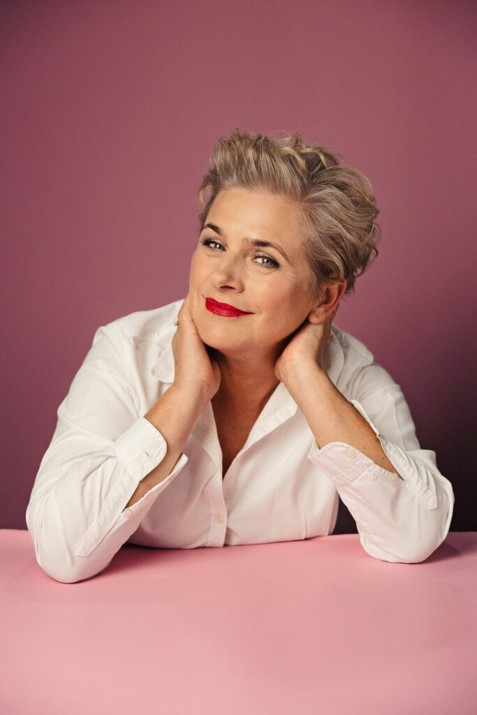 Zdjęcie portretowe aktorki Jagody Pietruszkówny, delikatny uśmiech, ręce na szyi.