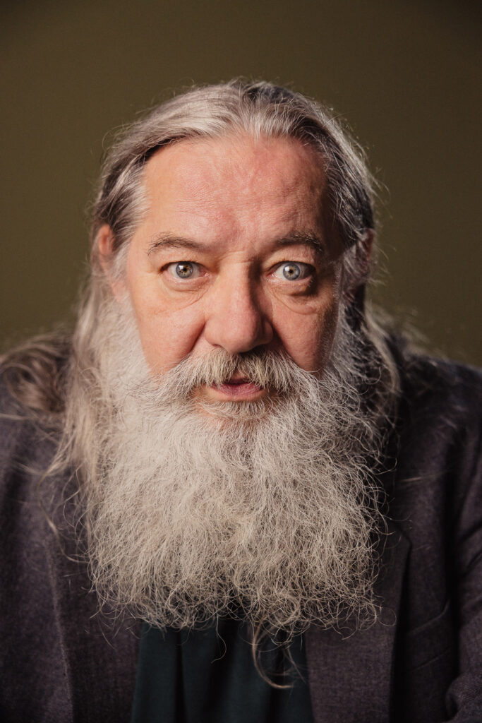 Zdjęcie portretowe aktora Kajetana Wolniewicza, poważna twarz, bliski kadr.