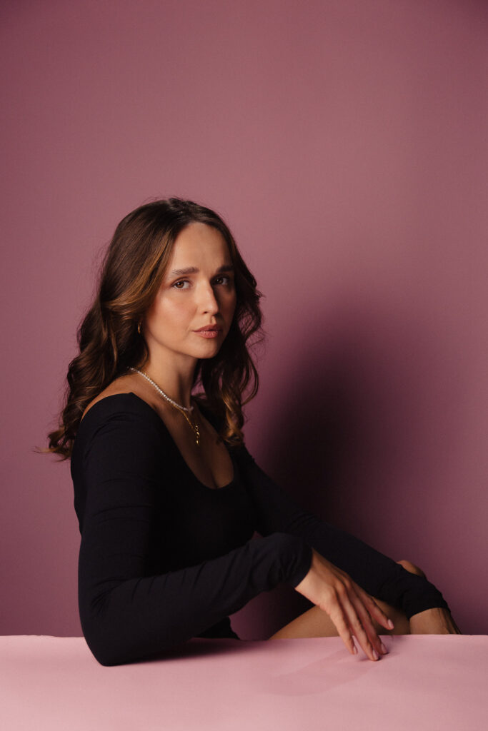 Zdjęcie profilowe portretowe aktorki Justyny Litwic, twarz poważna, ręce podpierają brodę.