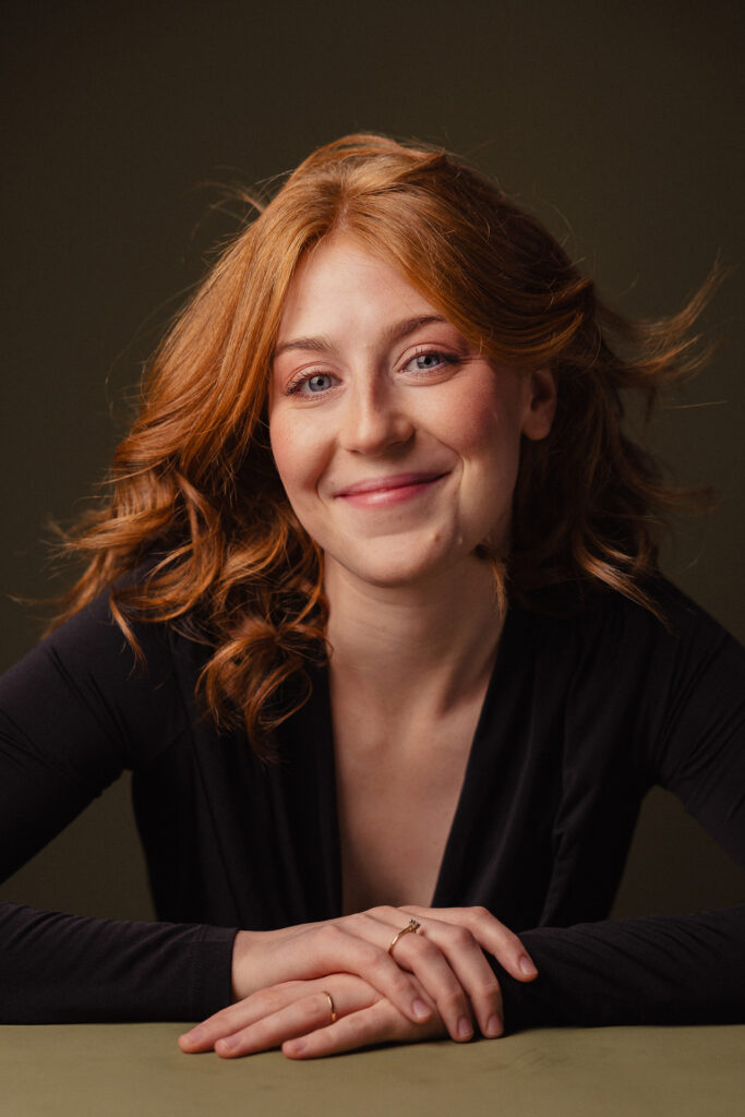 Zdjęcie portretowe aktorki Doroty Goljasz, szeroki uśmiech, ręce przed sobą.