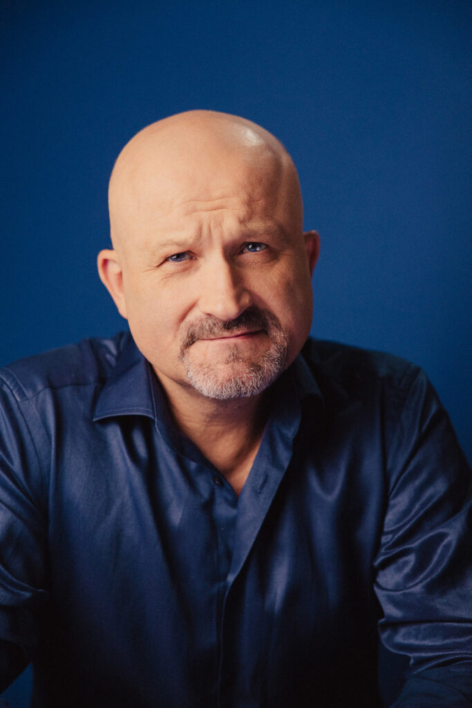 Zdjęcie portretowe aktora Jana Nosala, poważna twarz, bliski kadr.