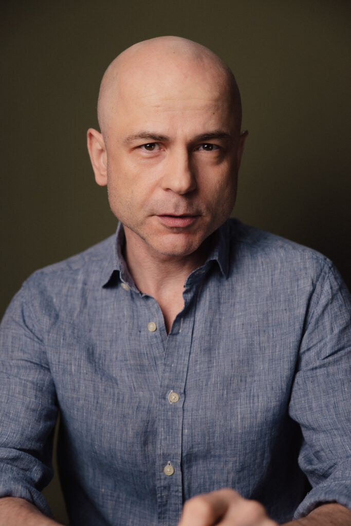 Zdjęcie portretowe aktora Macieja Namysło, poważna twarz, bliski kadr.