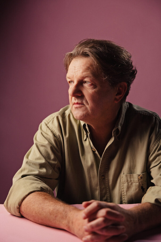 Zdjęcie profilowe portretowe aktora Jacka Wojciechowskiego, zamyślona twarz, ręce skrzyżowane przed sobą.