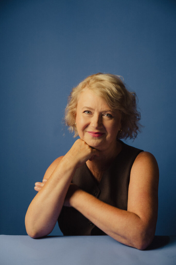 Zdjęcie portretowe aktorki Małgorzaty Kochan, lekki uśmiech, ręce skrzyżowane przed sobą.