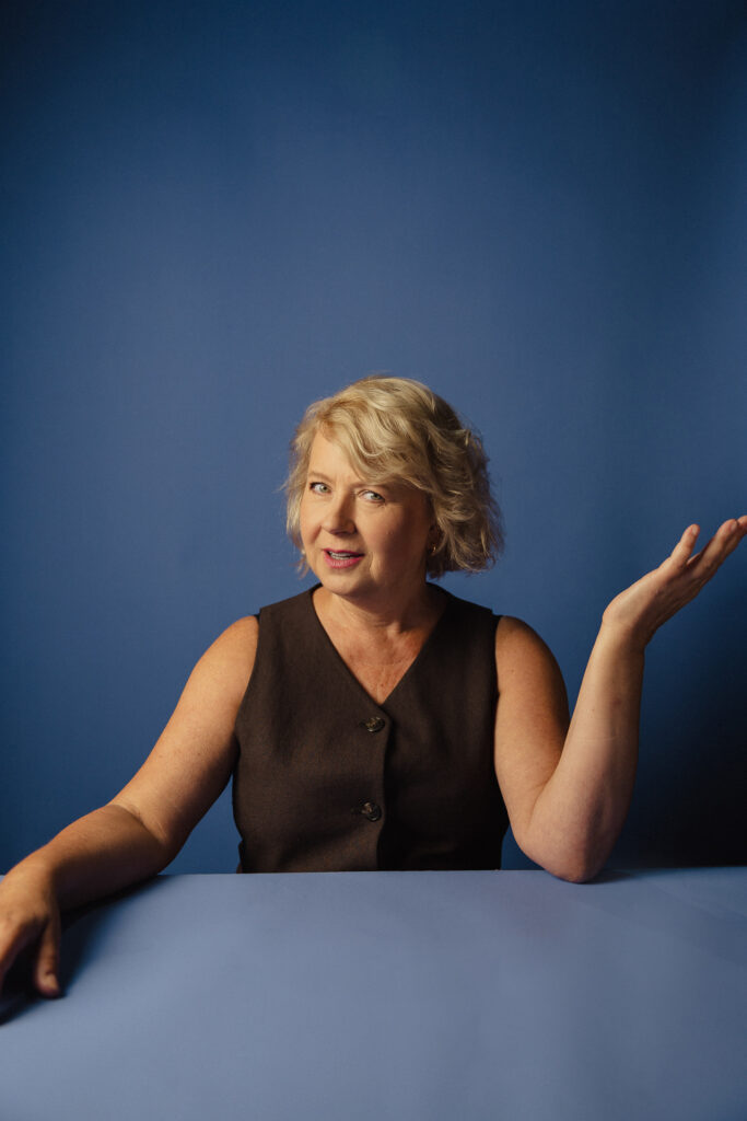 Zdjęcie portretowe aktorki Małgorzaty Kochan, lekki uśmiech, ręce rozłożone na bokią.