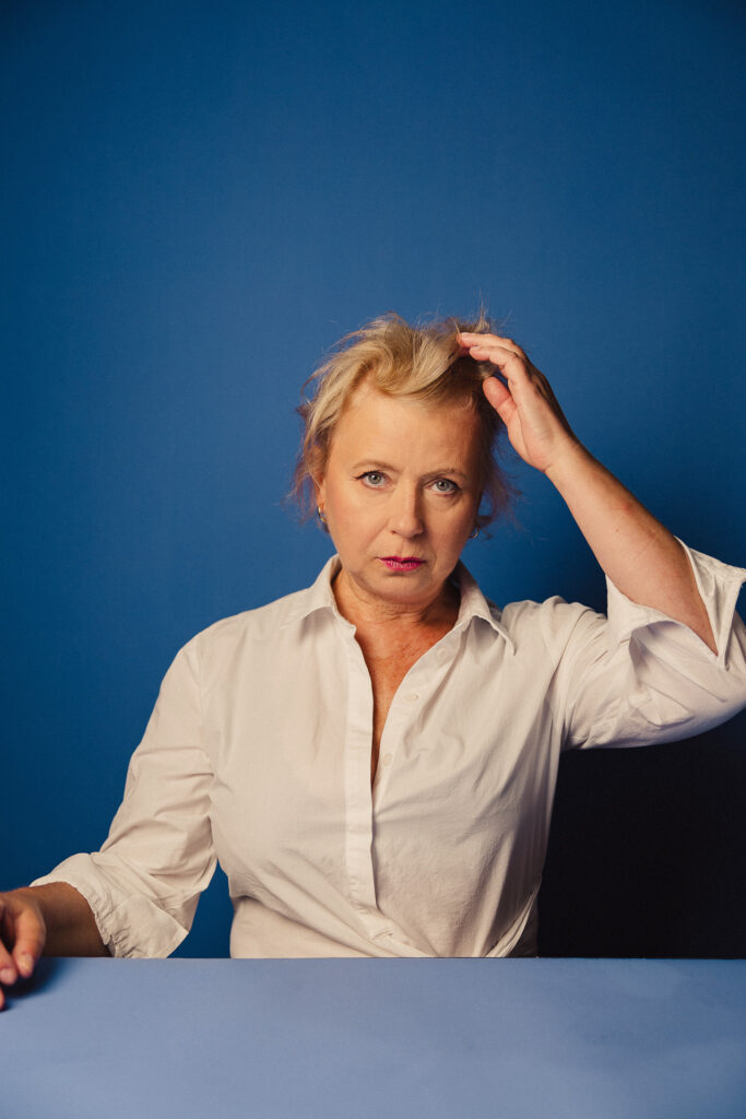 Zdjęcie portretowe aktorki Małgorzaty Kochan, poważna twarz, ręka we włosach.