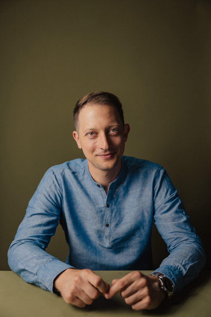 Zdjęcie profilowe portretowe aktora Wojciecha Lato, lekki uśmiech, ręce splecione przed sylwetką