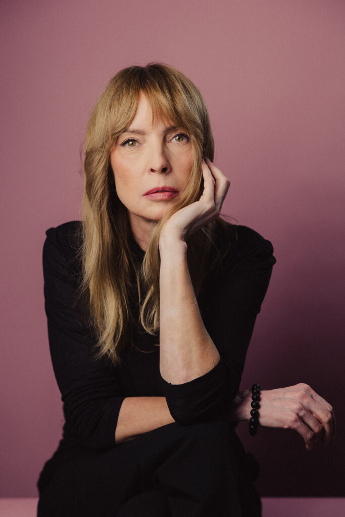 Zdjęcie portretowe aktorki Katarzyny Tlałki, poważna twarz, ręce skrzyżowane jedna podpiera brodę.