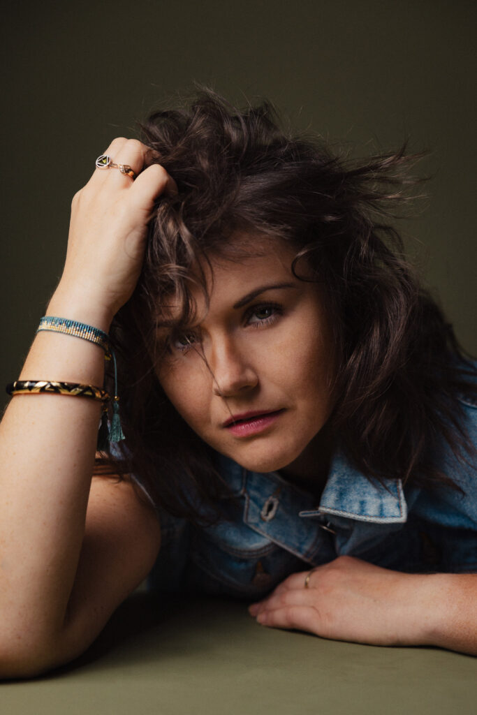 Zdjęcie portretowe aktorki Weroniki Kowalskiej, poważa twarz, bliski kadr, ręce we włosach.