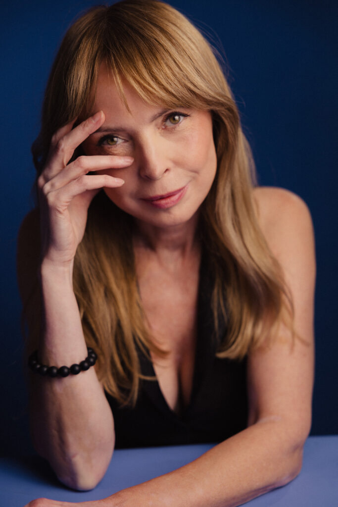 Zdjęcie portretowe aktorki Katarzyny Tlałki, poważna twarz, bliski kadr, ręka częściowo zakrywa twarz.