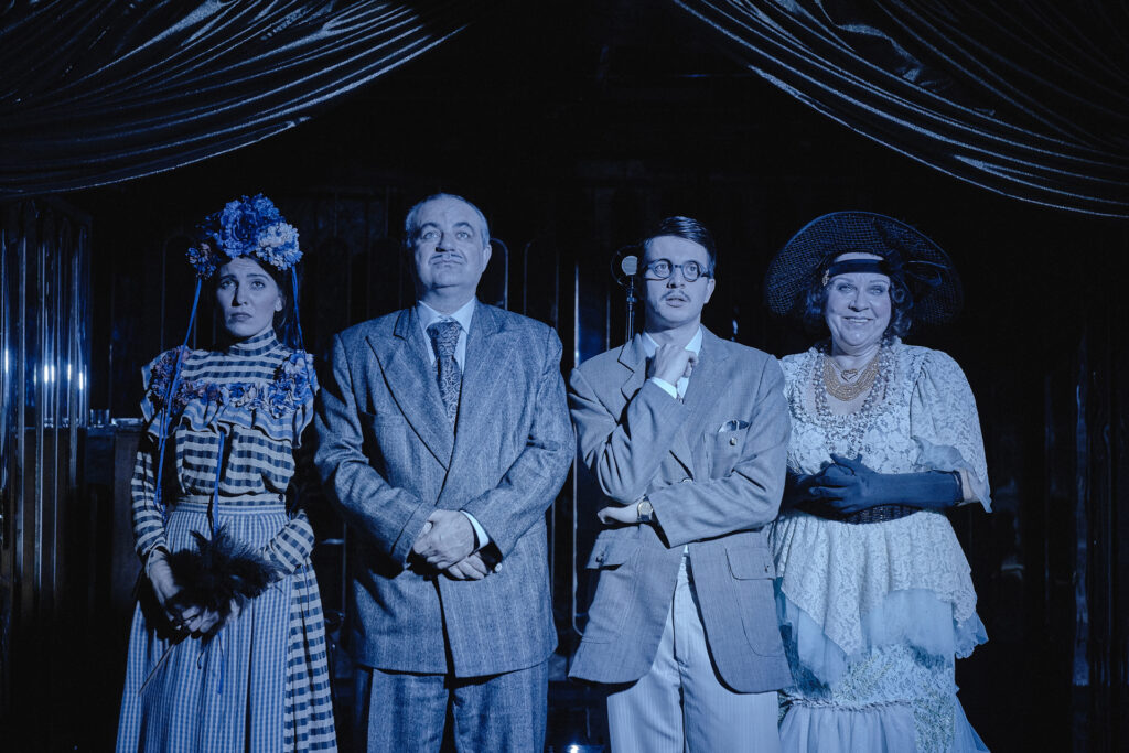 Zdjęcie ze spektaklu Boska. Dwie aktorki i dwóch aktorów stoi koło siebie. Aktorzy stoją w środku. Wszyscy mają kostiumy stylizowane na lata 20.