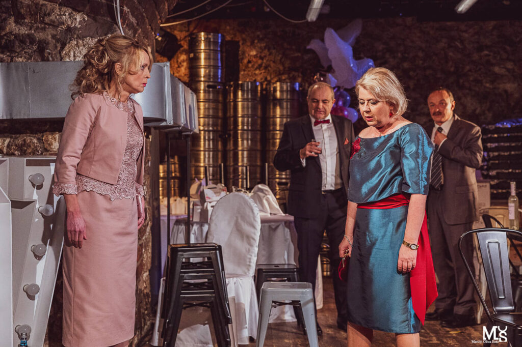 Zdjęcie ze spektaklu Wstyd. dwie aktorki stoją naprzeciwko siebie, mają smutne twarze. Z tyłu za nie stoi zdziwiony aktor w garniturze.