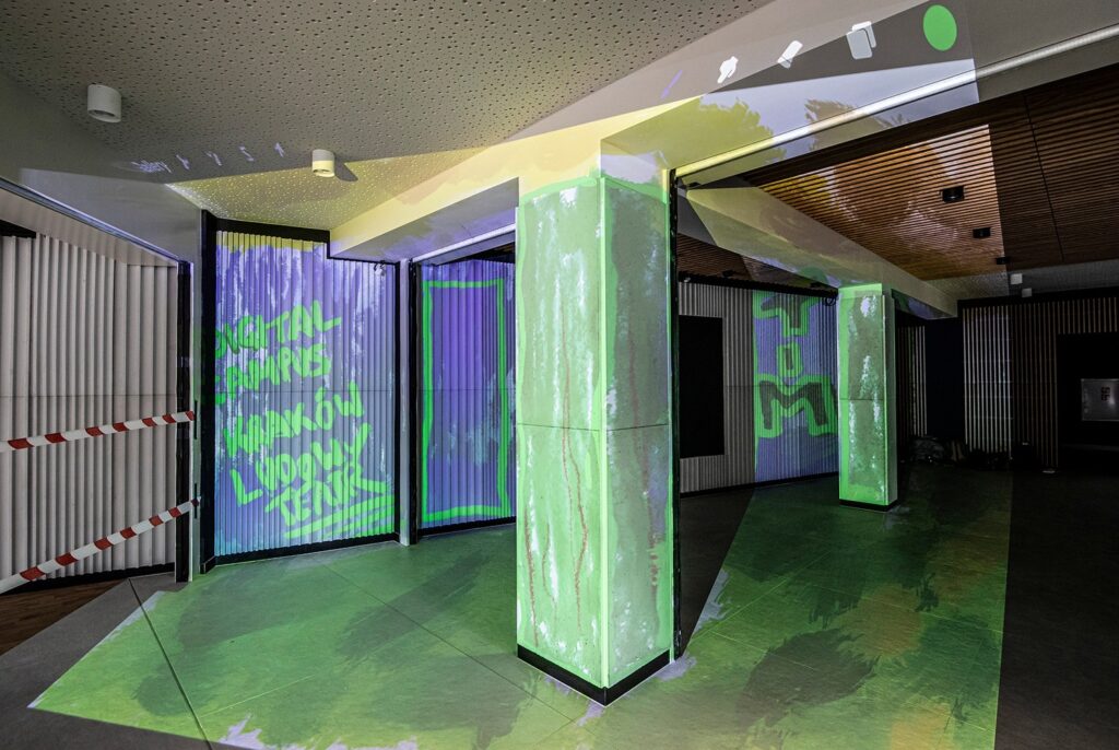 Zdjęcie z realizacji projektu PLAYON. Puste foyer teatralne na ścianach, suficie i podłodze, są wyświetlane kolorowe animacje, napisy i smugi.