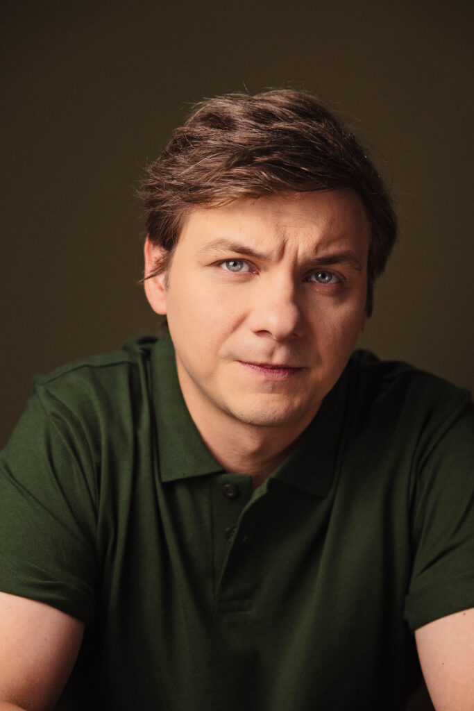 Zdjęcie portretowe aktora Ryszarda Starosty, lekki uśmiech, bliski kadr.