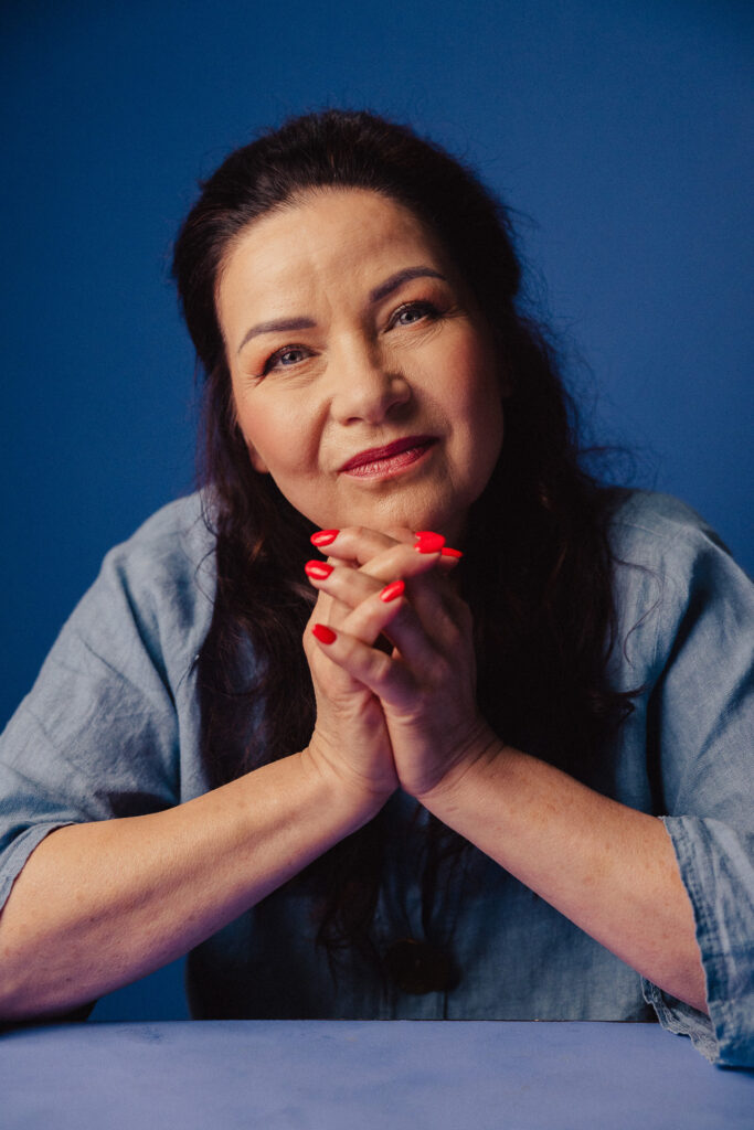 Zdjęcie portretowe aktorki Małgorzaty Krzysica, poważna pogodna twarz, ręce dotykają brody.