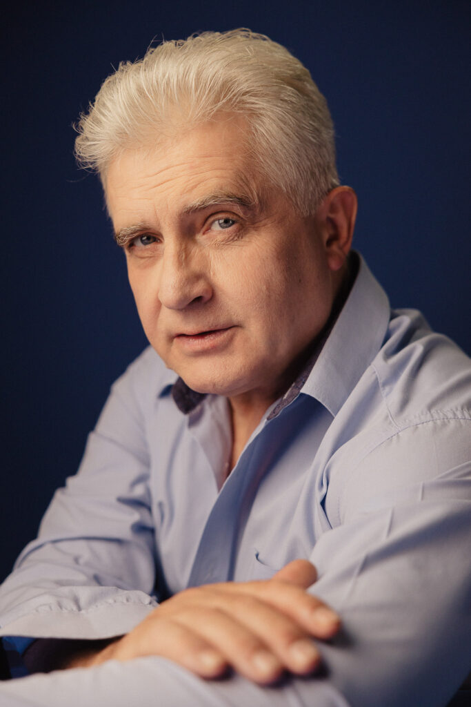 Zdjęcie portretowe aktora Piotra Piechy, poważna twarz, bliski kadr.