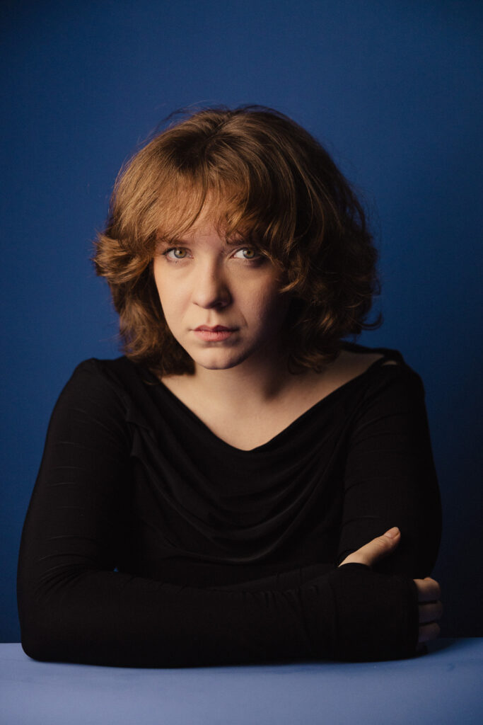 Zdjęcie portretowe aktorki Michaliny Dworzaczek, poważna twarz, ręce przed sylwetce.