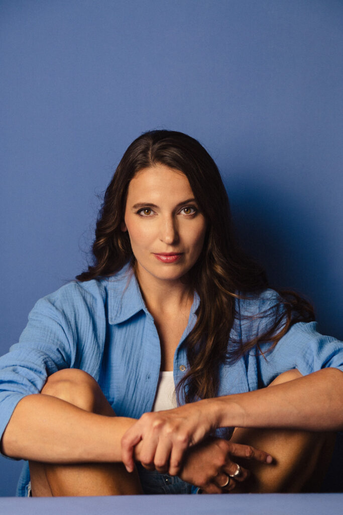 Zdjęcie portretowe aktorki Roksany Lewak, lekki uśmiech, bliski kadr, ręce otulają sylwetkę.