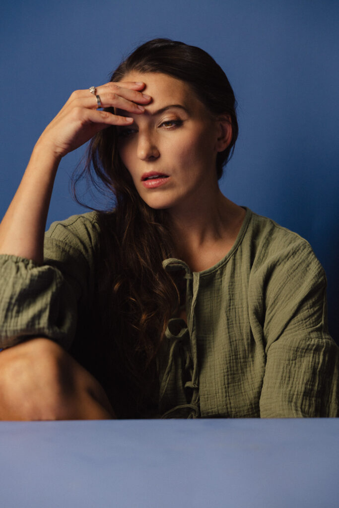 Zdjęcie portretowe aktorki Roksany Lewak, poważna zamyślona twarz, bliski kadr, ręka dotyka czoła.