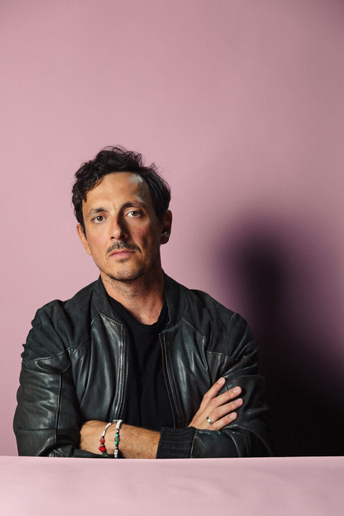 Zdjęcie profilowe portretowe aktora Piotra Franasowicza, poważna twarz, ręce splecione przy sylwetce.