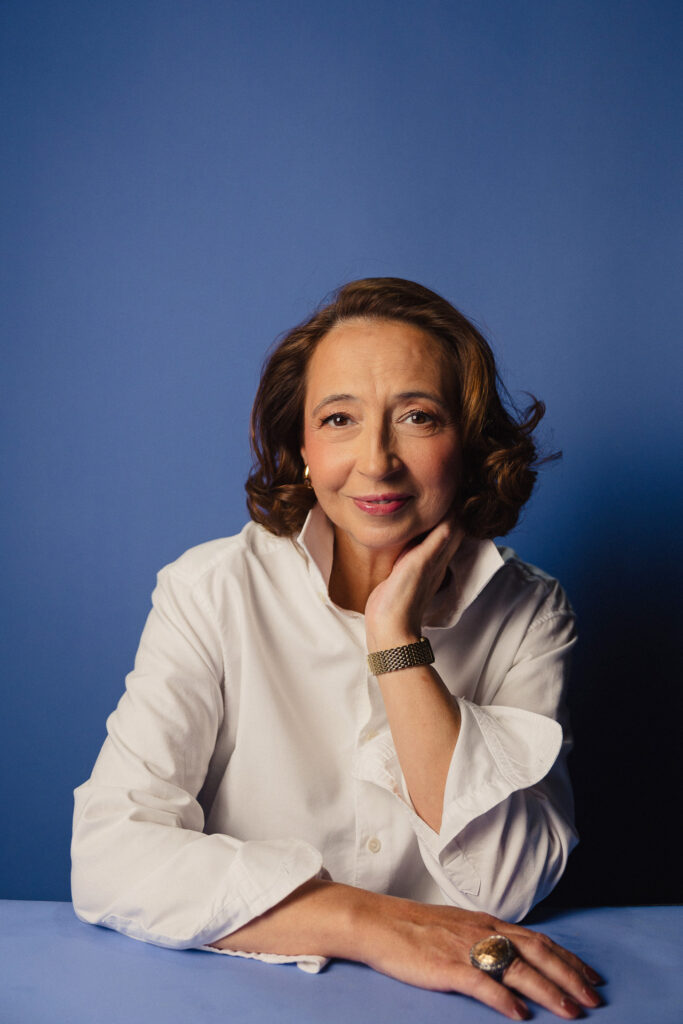 Zdjęcie półprofil portretowe aktorki Marty Bizoń, lekki uśmiech, ręka spoczywa na szyi.