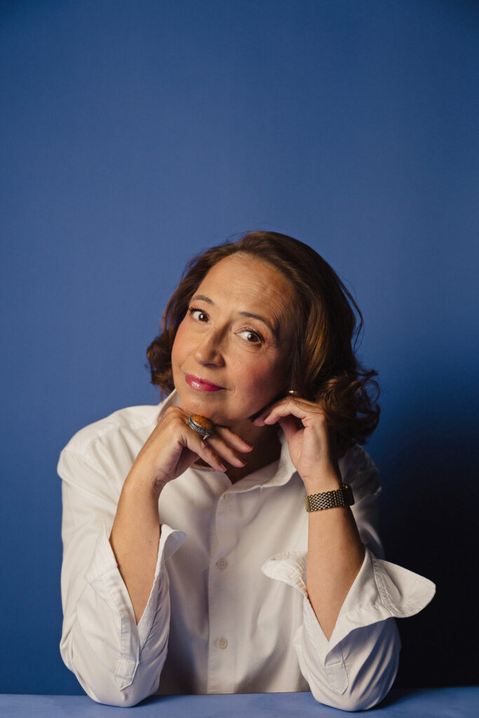 Zdjęcie portretowe aktorki Marty Bizoń, poważna twarz, ręce dotykają szyi.