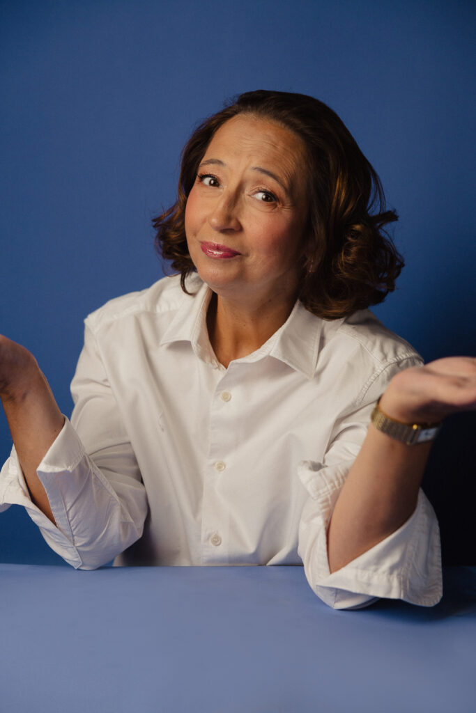 Zdjęcie portretowe aktorki Marty Bizoń, lekki uśmiech, ręce ręce wyciągnięte przed sylwetkę.