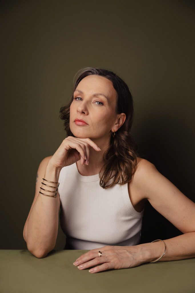 Zdjęcie półprofil portretowe aktorki Patrycji Durskiej, poważna twarz, ręka podpiera brodę.