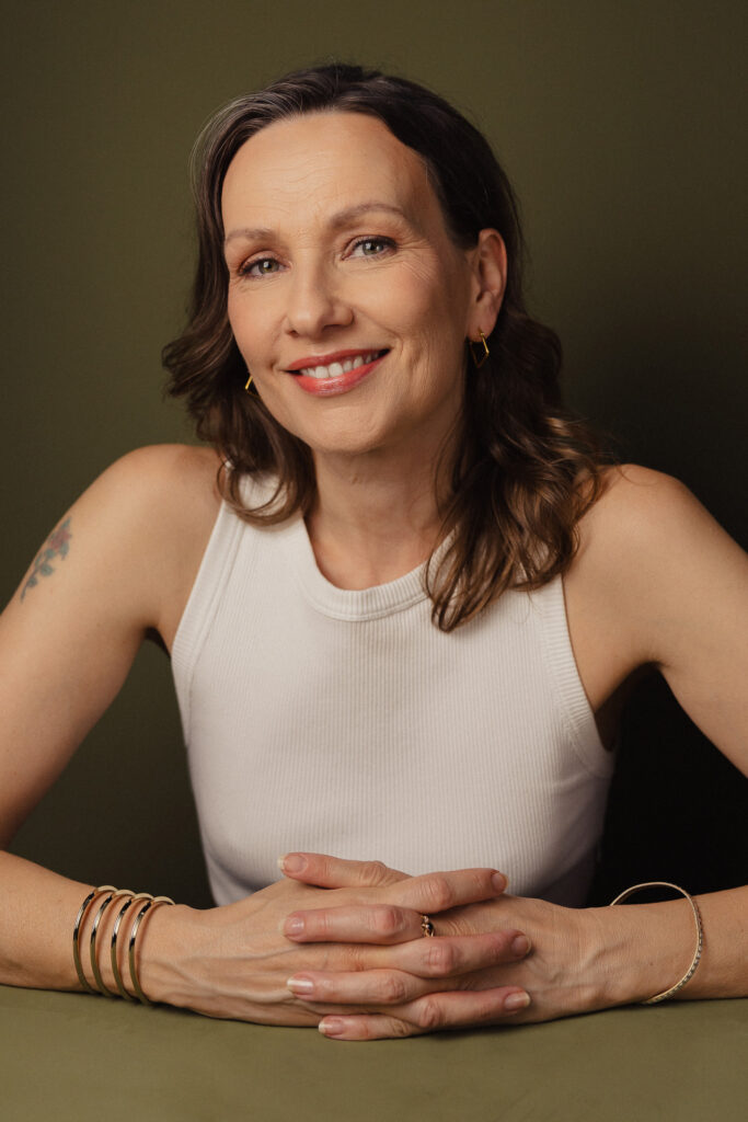 Zdjęcie półprofil portretowe aktorki Patrycji Durskiej, szeroki uśmiech, ręce przed sobą.