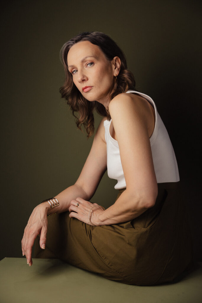 Zdjęcie półprofil portretowe aktorki Patrycji Durskiej, poważna twarz, ręce przy sylwetce, daleki kadr.