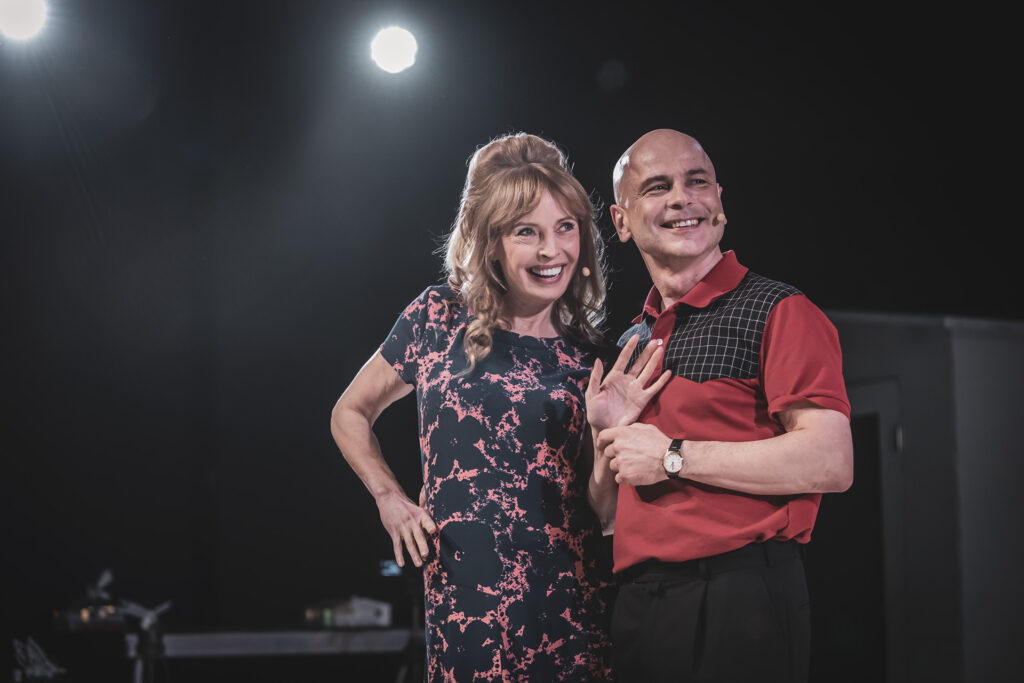 Zdjęcie ze spektaklu Co gryzie Gilberta Grappa. Dwoje aktorów, kobieta i mężczyzna stoją blisko siebie, uśmiechają się.