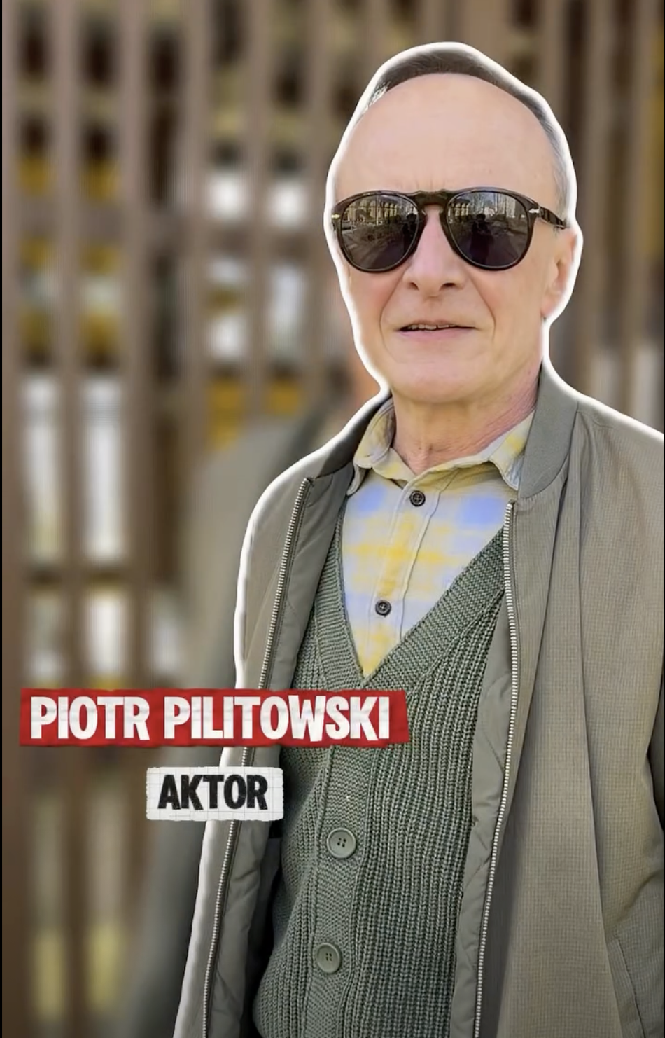 Aktor Piotr Pilitowski, mężczyzna w średnim wieku w ciemnych okularach na tle drewnianej konstrukcji