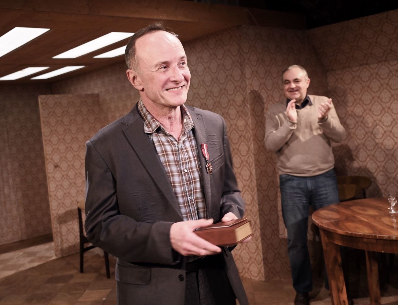 Aktor Piotr Pilitowski stoi na scenie ma do piersi przypięty medal.