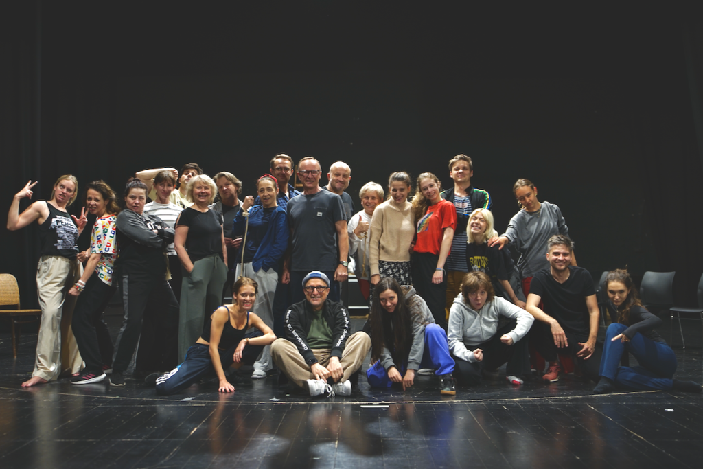 Grupa ludzi , aktorzy i aktorki wraz z twórcami spektaklu Folwark Zwierzęcy , pozują do "rodzinnego" zdjęcia na pamiątkę.