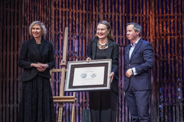 zdjęcie z uroczystości wręczenia medali zasłużonym pracownikom. Na scenie dyrektorka teatru trzymająca w ramie nagrodę, dyrektor oraz przedstawicielka Urzędu Marszałkowskiego Małopolski