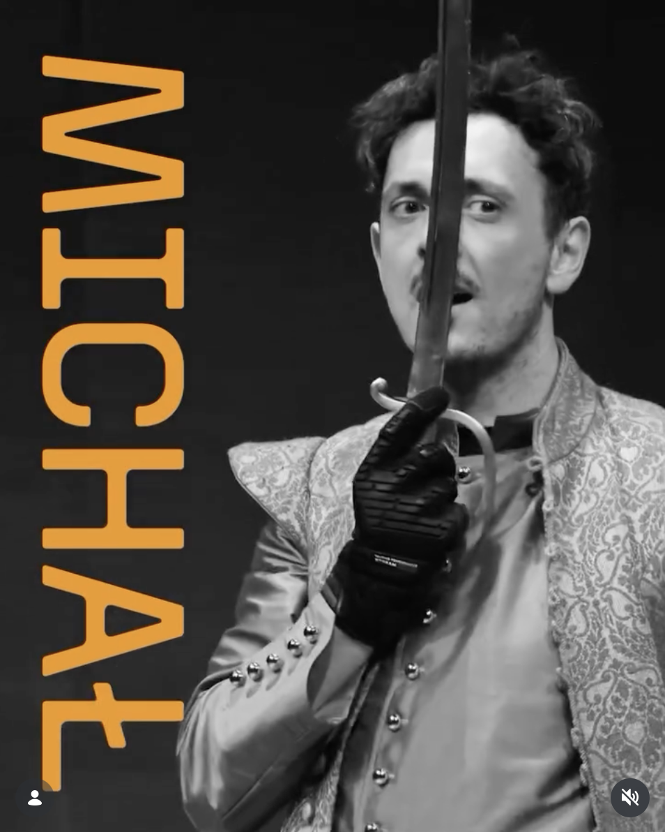 Kadr z filmiku promocyjnego spektaklu Pan Wołodyjowski. Aktor w kontuszu z szablą. Wideo czarno białe z lewej strony napis "Michał"